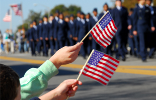 children wave flags during a veterans day parade