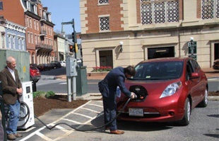 a man charges a Nissan Leaf demonstrating the electric car charger