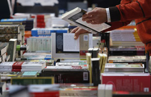 man searches through stacks of books