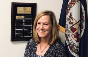 maggie ragon poses with accreditation plaque